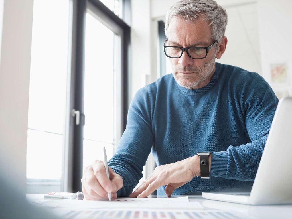 Bild: Mann im Büro prüft eine Bilanz.