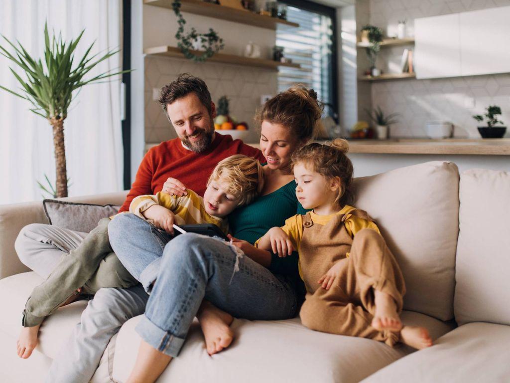Familie sitzt auf Couch und guckt in ein Buch